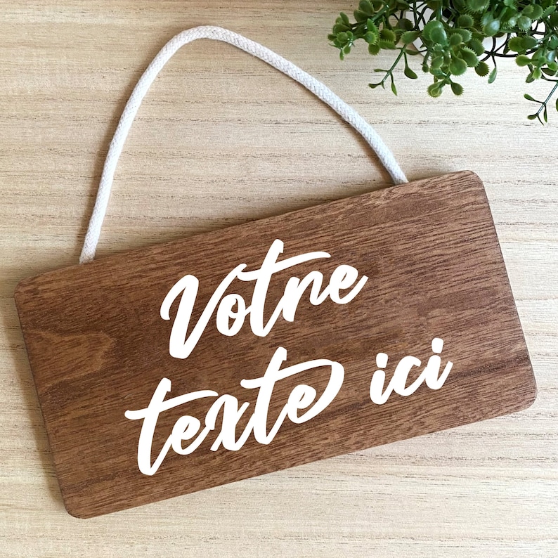 Puede incluir: Un letrero rectangular de madera con las palabras "Votre texte ici" en escritura blanca. El letrero tiene un patr&oacute;n de vetas de madera marr&oacute;n claro y una cuerda blanca para colgar.
