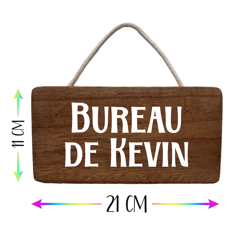 Puede incluir: Un letrero rectangular de madera con el texto "BUREAU DE KEVIN" en blanco. El letrero mide 21 cm de ancho y 11 cm de alto, con una cuerda para colgarlo. La madera es de color marr&oacute;n oscuro.