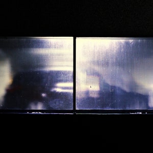 Puede incluir: Una vista a través de una ventana de vidrio esmerilado, que muestra una silueta borrosa de un automóvil estacionado dentro de un garaje.