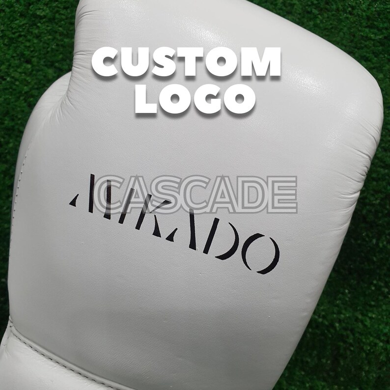 Peut inclure: Gant de boxe en cuir blanc avec du texte noir qui dit "CASCADE" et "CUSTOM LOGO".