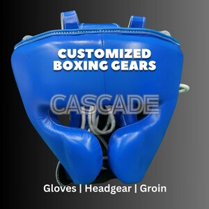 May include: Blue boxing headgear with white stitching and the text "CUSTOMIZED BOXING GEARS CASCADE Gloves | Headgear | Groin"