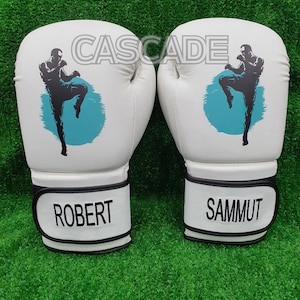 May include: A pair of white boxing gloves with black trim. The gloves feature a blue and white graphic of a person kicking. The gloves are labelled "Robert" and "Sammut".
