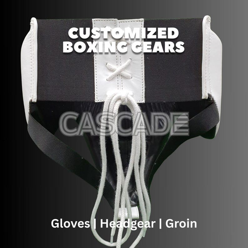 May include: Black and white boxing groin protector with white laces and the word "CASCADE" printed on the front. The text "CUSTOMIZED BOXING GEARS" is printed above the word "CASCADE". The text "Gloves | Headgear | Groin" is printed below the word "CASCADE".