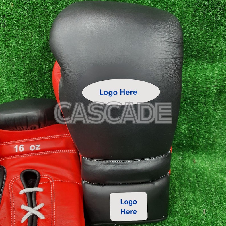 Peut inclure: Une paire de gants de boxe noirs et rouges avec des &eacute;tiquettes blanches. L'&eacute;tiquette sur le gant du haut indique "Logo Here" et l'&eacute;tiquette sur le gant du bas indique "Logo Here". Le gant du bas a &eacute;galement une &eacute;tiquette blanche avec le texte "16 oz".