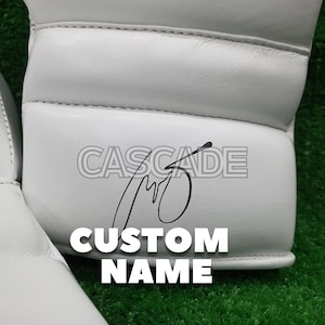 Peut inclure: Gants de boxe blancs avec des coutures noires et le texte "CASCADE CUSTOM NAME" &eacute;crit dessus.