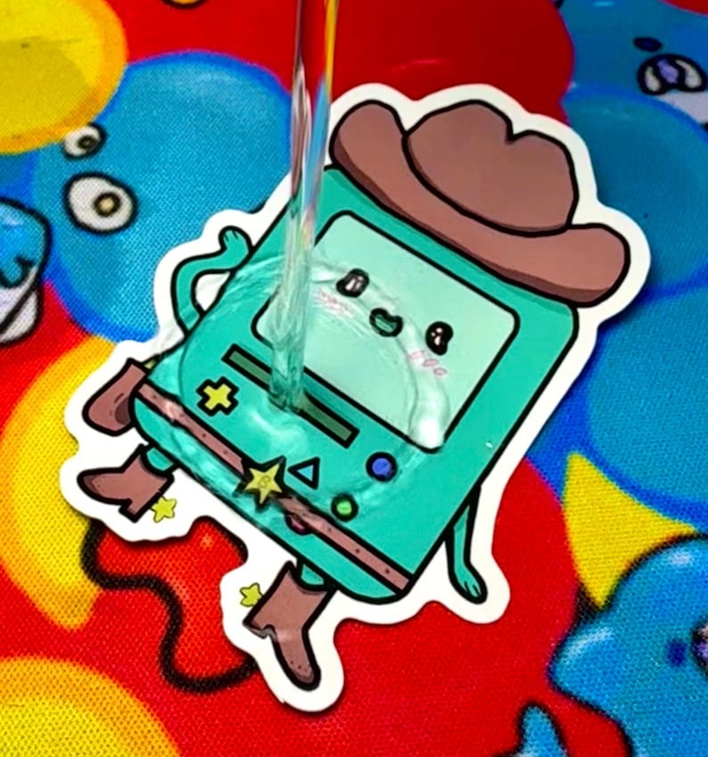 May include: A teal sticker featuring a cartoon character in a cowboy hat and boots. The character has a screen face with a smiling expression. The sticker has a white border and is on a colorful background.
