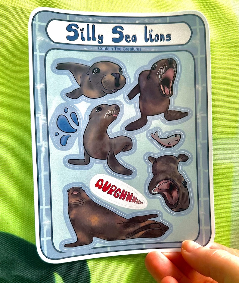 May include: A sticker sheet featuring several cartoon sea lions in various poses. The sticker sheet has the text "Silly Sea Lions" and "Contain The Creatures". The sea lions are brown with white accents, and some have speech bubbles.