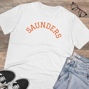 May include: White t-shirt with an orange arch design that says "SAUNDERS".