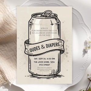 May include: An invitation for a baby shower with a beer can design. The text reads "Dudes & Diapers" and includes event details: date, time, and location. The invitation is in black and white on a cream background.