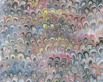 May include: A close-up of decorative paper with a marbled pattern. The design features a repeating, fan-like motif in shades of grey, black, pink, yellow, and blue. The overall effect is a textured, colourful, and artistic design.