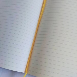May include: A lined notebook with a yellow ribbon bookmark. The notebook is open to a blank page.