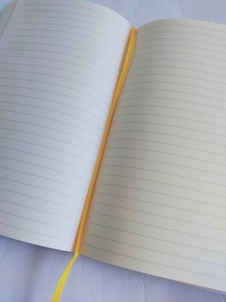 May include: A lined notebook with a yellow ribbon bookmark. The notebook is open to a blank page.