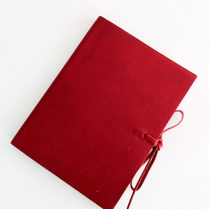 May include: A deep red leather-bound journal with a matching red ribbon closure.