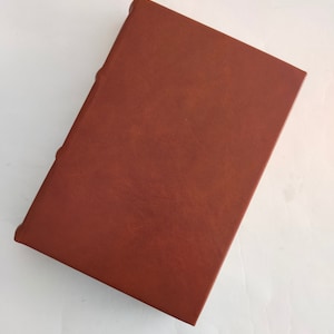 May include: A brown leather-bound book with a smooth, textured cover.