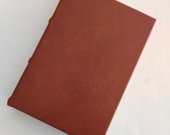 May include: A brown leather-bound book with a smooth, textured cover.