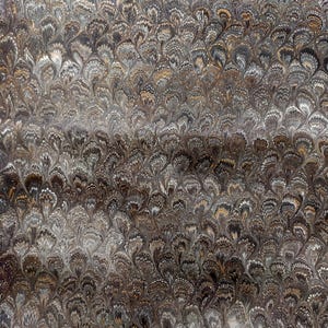Può includere: Un foglio di carta caratterizzato da un tradizionale motivo marmorizzato con un disegno ripetitivo a ventaglio. Il design è composto da intricati vortici nelle tonalità del marrone scuro, grigio antracite, oro metallizzato e crema, creando un effetto denso.