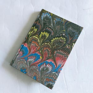 May include: A small, colorful notebook with a marbled cover. The cover features a swirling pattern of blue, red, green, and yellow.