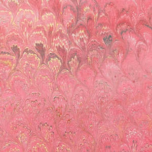 May include: A close-up of a sheet of paper with a marbled design. The pattern features a repeating, flowing design in shades of pink, red, yellow, and gray. The paper has a textured appearance, with the colors blending together to create a unique visual effect.