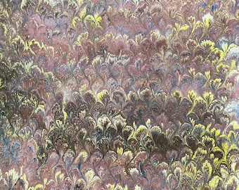 May include: A close-up of decorative paper with a marbled pattern. The design features a repeating floral motif in shades of burgundy, yellow, brown, and blue. The paper has a textured appearance, suggesting it may be handmade.