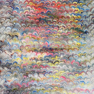 May include: A sheet of paper featuring a traditional Turkish marbling pattern known as ebru. The design consists of repeating, overlapping fan-shaped motifs in vibrant shades of red, blue, yellow, and black, set against a light gray background.