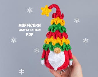 May include: A handmade crochet gnome in red, green, yellow, and white, with a yellow star on top. The gnome has a white beard and a round, tan nose. The text "MUFFICORN CROCHET PATTERN PDF" is displayed on the left side of the image.