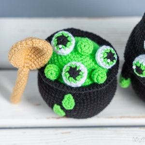 May include: A crocheted cauldron with green goo and googly eyes, a crocheted spoon, and a crocheted black and white monster with googly eyes.