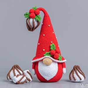 May include: A crocheted Christmas gnome with a red hat, white beard, and a green holly sprig with red berries. The gnome is surrounded by three white and brown crocheted candy canes.