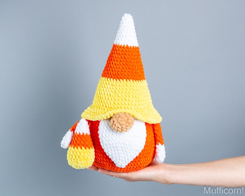 May include: A crocheted candy corn gnome with a white beard and orange, yellow, and white striped hat.