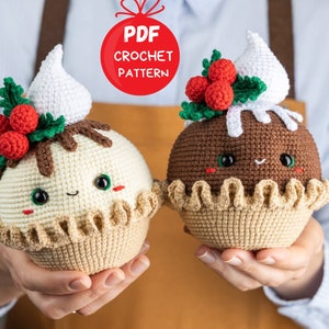 May include: Two crocheted Christmas pudding ornaments with cute faces. One is white with brown chocolate topping and red holly berries. The other is brown with white whipped cream topping. Both have a brown crocheted crust and are held in hands.  PDF CROCHET PATTERN.