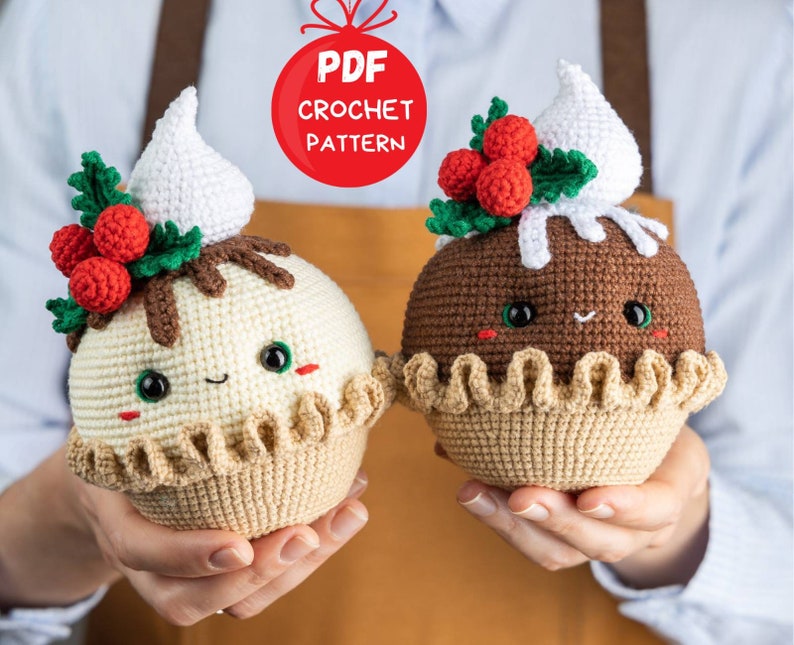 May include: Two crocheted Christmas pudding ornaments with cute faces. One is white with brown chocolate topping and red holly berries. The other is brown with white whipped cream topping. Both have a brown crocheted crust and are held in hands.  PDF CROCHET PATTERN.