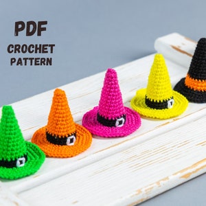 May include: A PDF crochet pattern for five witch hats in different colours: green, orange, pink, yellow and black. The hats are arranged on a white wooden surface.