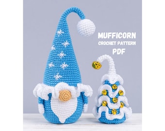 May include: Two crocheted gnome figures. One is tall with a blue cone-shaped hat adorned with white snowflakes and a white pom-pom. The other is a smaller tree-shaped figure with gold bells. The text "MUFFICORN CROCHET PATTERN PDF" is visible.