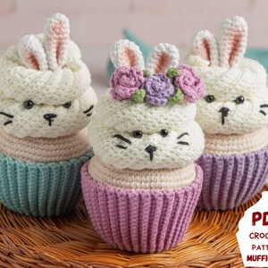 Könnte beinhalten: Drei gehäkelte Amigurumi-Spielzeug in Form von Cupcakes mit Hasen. Die Cupcakes sind in Pastellfarben mit einem weißen Hasenkopf obenauf. Der mittlere Cupcake hat eine lila und rosa Blütenkrone auf dem Hasenkopf. Der Text "PDF CROCHET PATTERN MUFFICORN" befindet sich in der unteren rechten Ecke des Bildes.