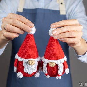May include: Two crocheted gnome ornaments in red and white. The gnomes have white beards and white hats with white pom-poms.