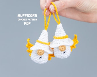May include: Two white crocheted gnomes with yellow yarn hats and yellow yarn hair. The gnomes are hanging from yellow yarn loops. The text "MUFFICORN CROCHET PATTERN PDF" is visible in the image.