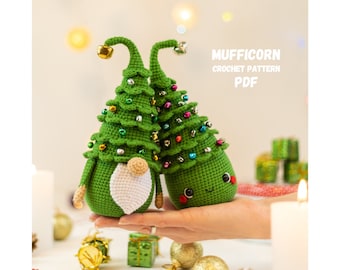 May include: Two green crocheted Christmas tree gnomes with white beards and bells. The gnomes are holding hands and have smiling faces. The text "MUFFICORN CROCHET PATTERN PDF" is in the upper right corner of the image.