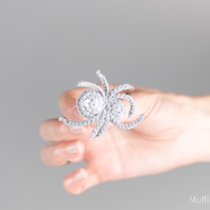 May include: A gray crocheted spider with a round body and eight legs.