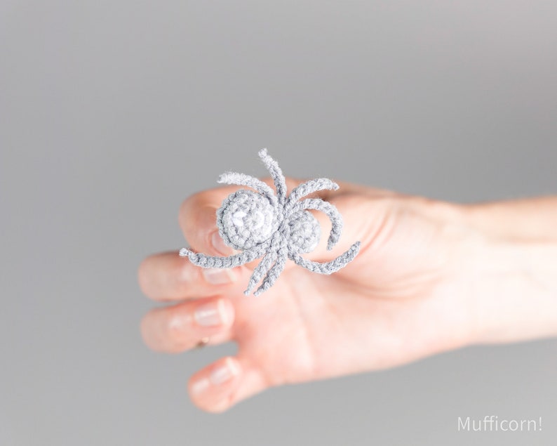 May include: A gray crocheted spider with a round body and eight legs.