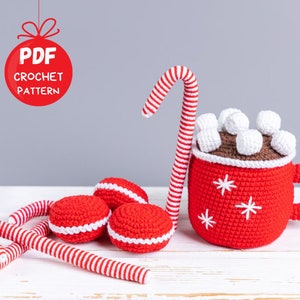 Op de afbeelding: Haakpatroon PDF voor een rode en witte snoepstok, een rode mok met witte sneeuwvlokken en witte marshmallows, en drie rode en witte macarons.