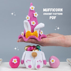 May include: A pink crocheted unicorn hat with white ears and yellow bow, a white crocheted basket filled with chocolate eggs, and two pink crocheted eggs. The text "MUFFICORN CROCHET PATTERN PDF" is displayed above the hat.