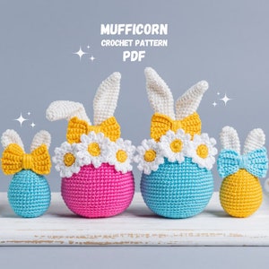 May include: Four crocheted bunny-shaped Easter eggs in blue, pink, yellow, and white with daisy accents. The eggs are arranged on a white wooden surface. The text "MUFFICORN CROCHET PATTERN PDF" is displayed above the eggs.