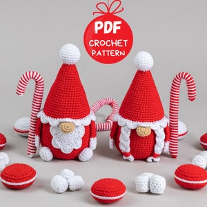 Könnte beinhalten: Zwei rot-weiße gehäkelte Gnome mit weißen Bärten und Zuckerstangen-Akzenten. Die Gnome sind von kleinen rot-weißen gehäkelten Kugeln umgeben. Der Text "PDF CROCHET PATTERN" befindet sich auf einem roten Kreis mit einer weißen Schleife.