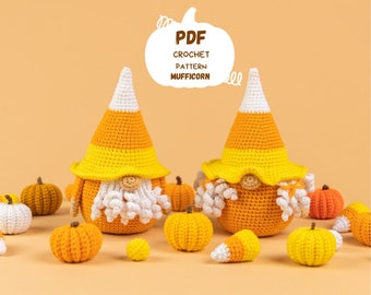 May include: Two crocheted gnome figures with candy corn hats and white beards, surrounded by crocheted pumpkins in various sizes and colours. The image includes the text "PDF Crochet Pattern Mufficorn".