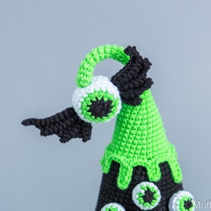 May include: Green and black crocheted Halloween cone with a large eye on top and smaller eyes around the base.