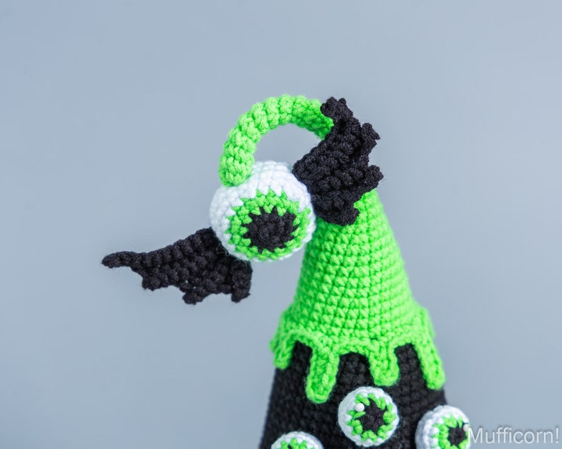 May include: Green and black crocheted Halloween cone with a large eye on top and smaller eyes around the base.