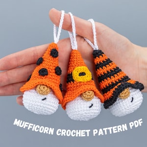 May include: Three handmade crochet gnome ornaments with orange and black hats, white beards, and closed eyes. The hats have different designs, including polka dots and stripes. Each ornament has a white loop for hanging. The text "MUFFICORN CROCHET PATTERN PDF" is at the bottom.