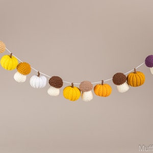 May include: A garland of crocheted pumpkins and mushrooms in shades of orange, yellow, white, brown, and purple. The garland is strung on white twine and is perfect for fall decor.