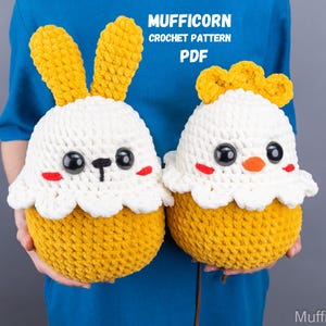 Op de afbeelding: Twee gehaakte knuffels, een konijn en een kuiken, beide met gele lichamen en witte gezichten. Het konijn heeft lange, slappe oren en het kuiken heeft een kleine, gele snavel. Beide knuffels hebben zwarte ogen en rode wangen. De tekst "MUFFICORN CROCHET PATTERN PDF" is zichtbaar bovenaan de afbeelding.