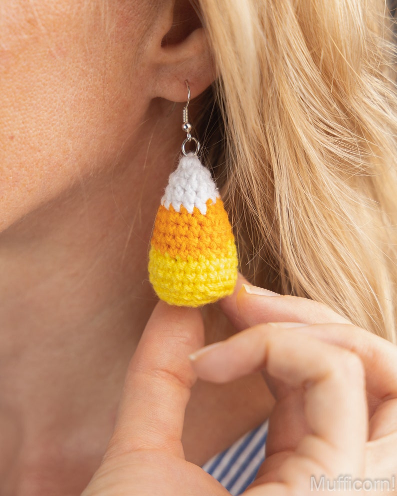 May include: Crocheted candy corn earrings in yellow, orange and white. The earrings are hanging from silver ear wires.