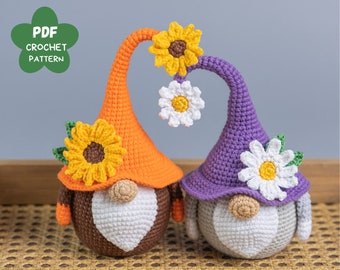 May include: Two crocheted gnomes with orange and purple hats. The gnomes have white beards and are decorated with crocheted sunflowers and daisies.